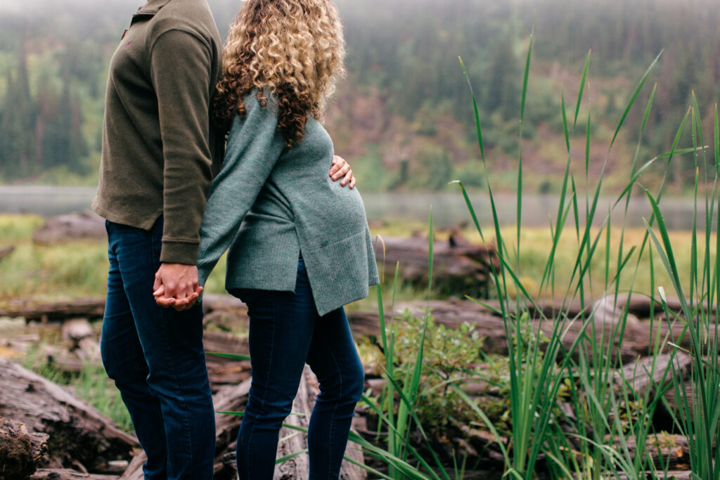 Close-up of expectant parents’ hands resting on a baby bump during an intimate maternity photo session in Coeur d’Alene, Idaho.