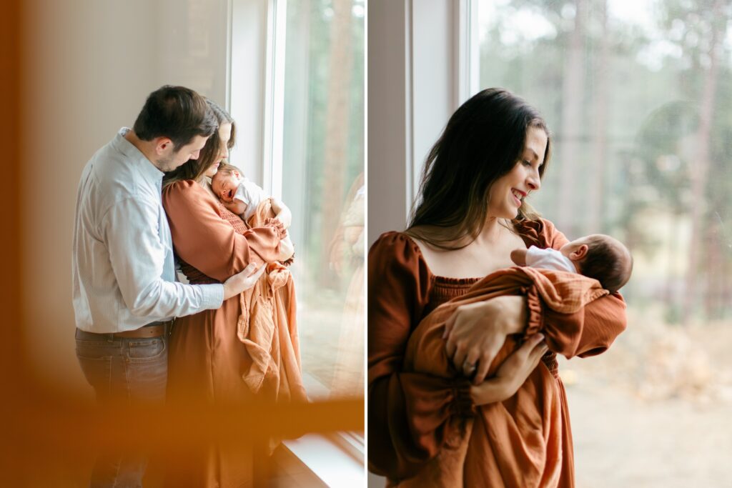 mom and dad facing a window, cuddling their newborn baby boy and smiling for indoor newborn photography session in CDA