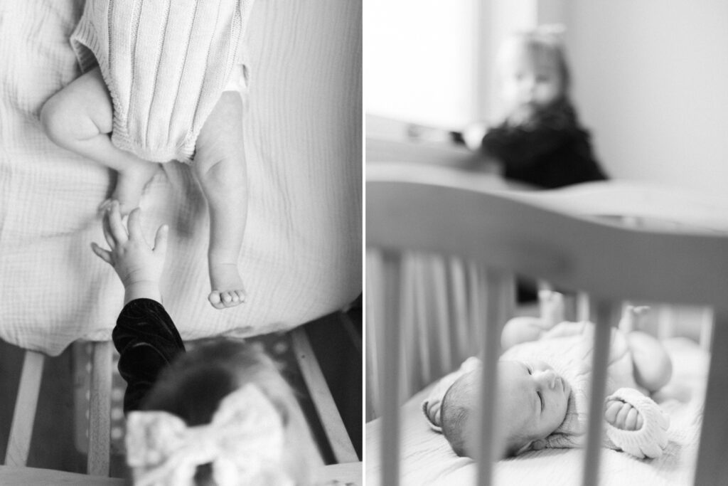 black and white image of toddler girl playing with newborn brother in his crib