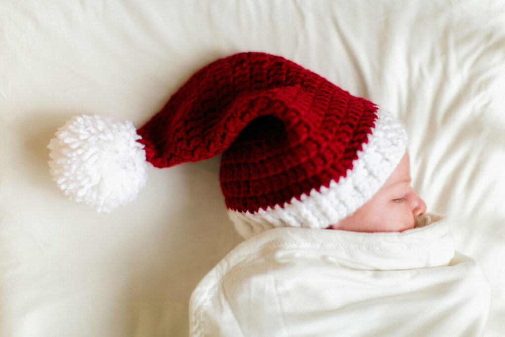 Sleeping baby in a Santa hat for indoor newborn photography session in CDA