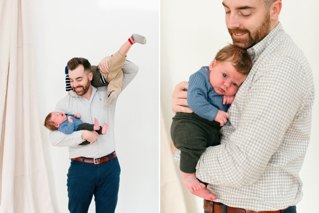 Dad holding his newborn and his toddler, laughing, playing against a neutral backdrop in a north idaho studio