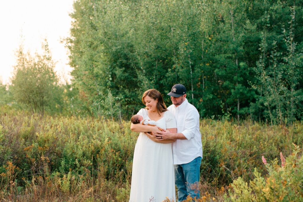 a couple holding a newborn near the woods in a park in post falls idaho