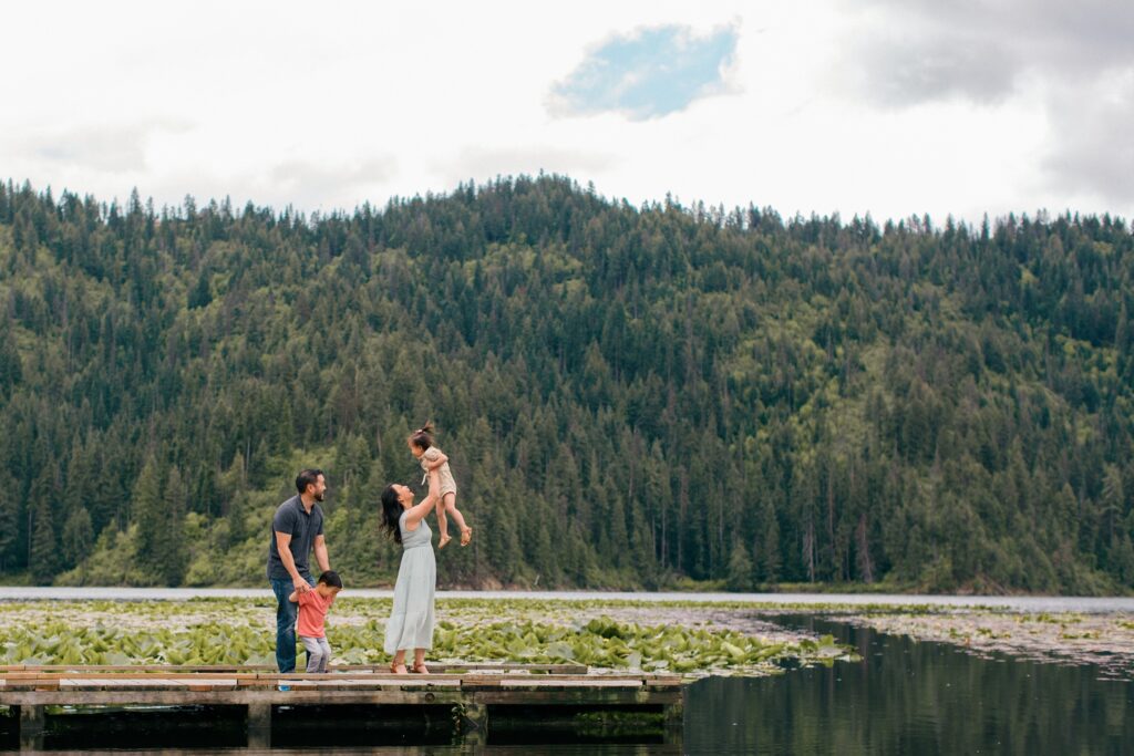 mom and dad and two toddlers playing on the pier of lake coeur dalene during an extended family session