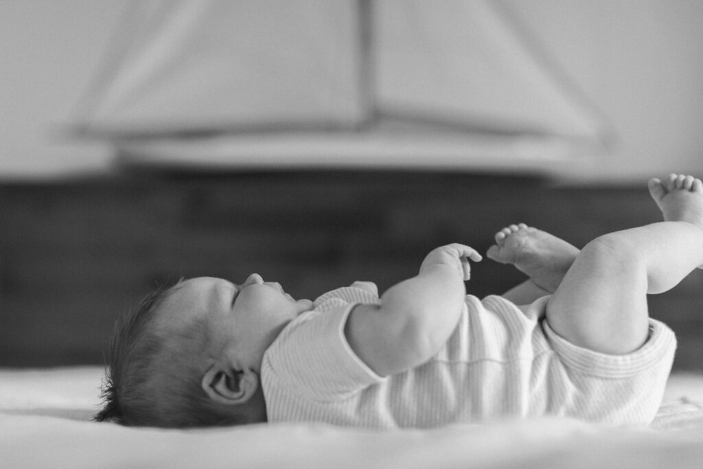 black and white newborn with chunky rolls on his parents bed for an in home newborn session in coeur d'alene idaho
