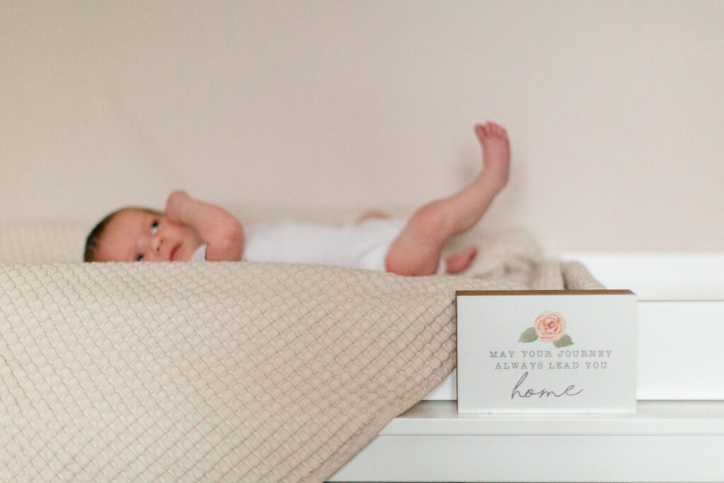 Newborn baby sleeping on a neutral quilt in a softly decorated nursery during a lifestyle newborn session in North Idaho