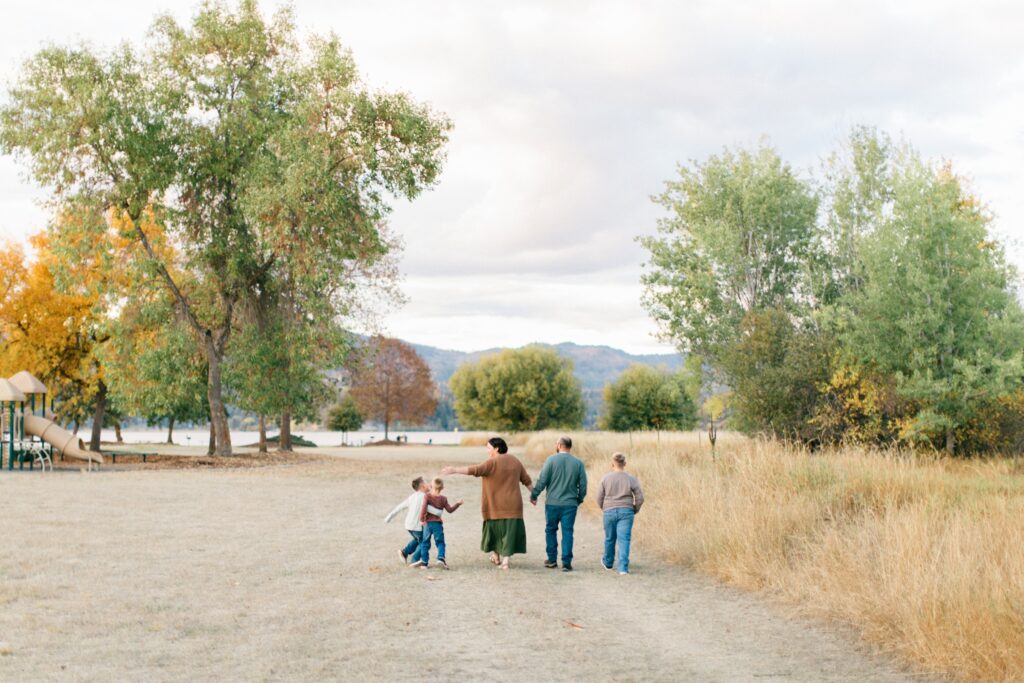 family walking in the fields mountains behind them in the fall in north idaho